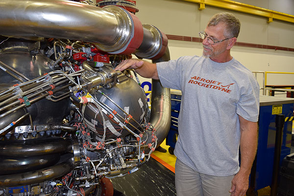 An Aerojet Rocketdyne technician inspects the 3-D printed pogo accumulator assembly on an RS-25 development engine at the Aerojet Rocketdyne facility located at NASA's Stennis Space Center